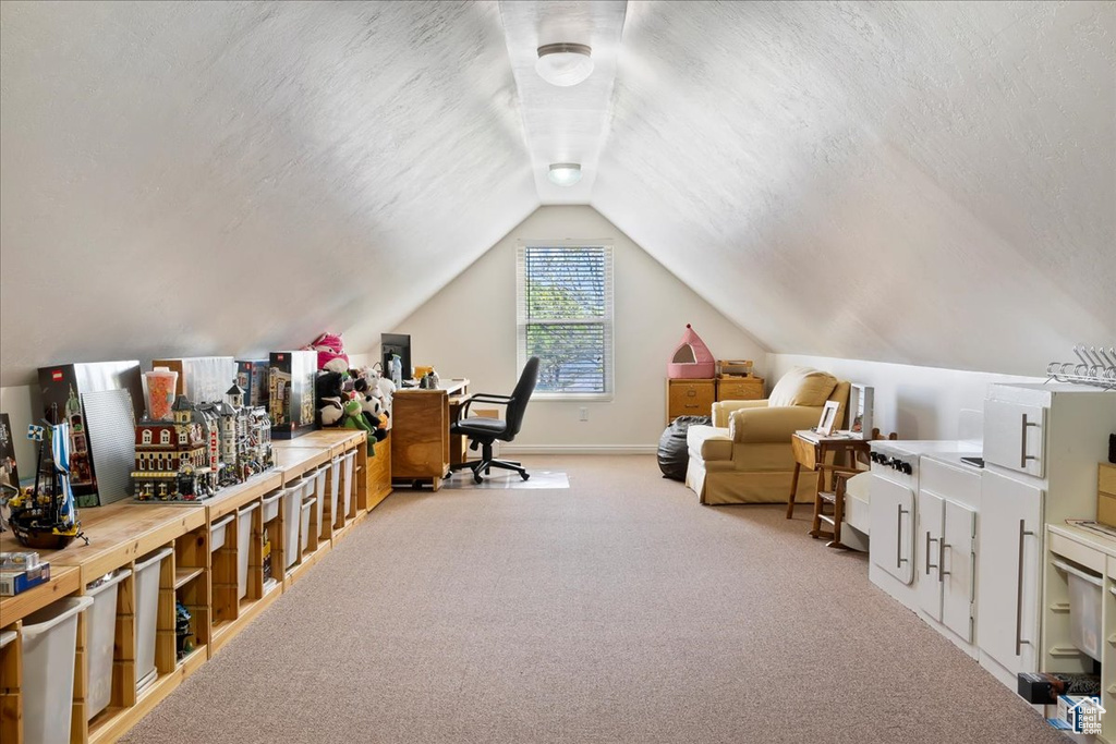 Carpeted home office with vaulted ceiling and baseboards