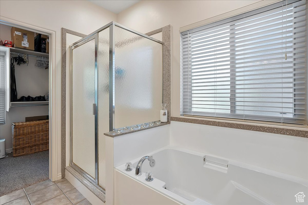 Full bathroom with tile patterned floors, a spacious closet, a stall shower, and a garden tub