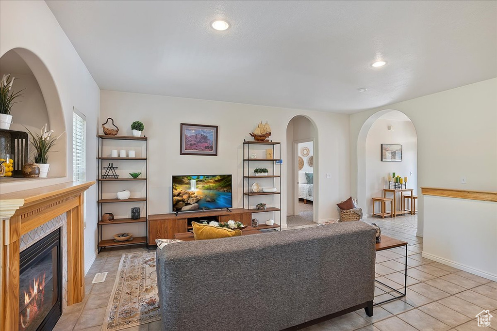 Living area with light tile patterned floors, recessed lighting, arched walkways, and a glass covered fireplace