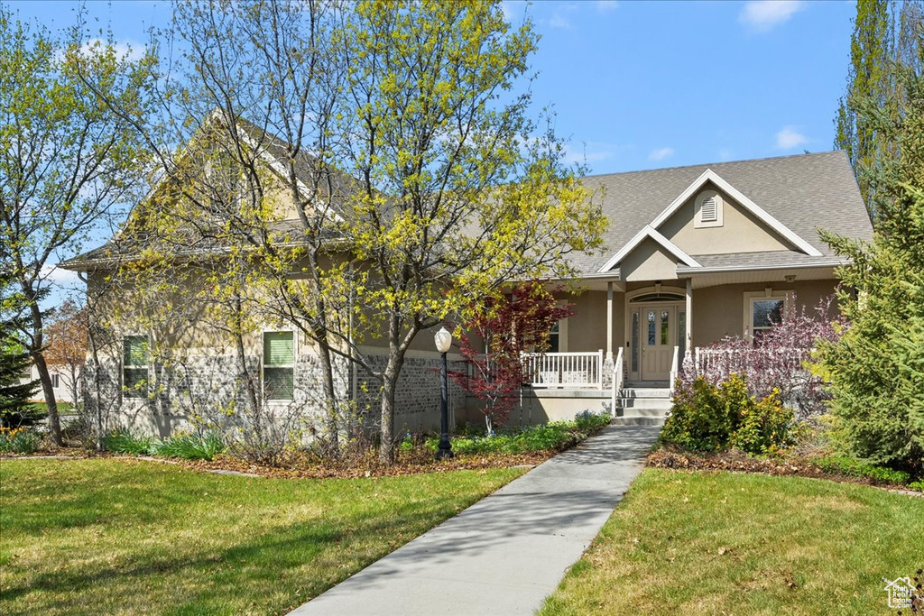 View of front facade featuring a front lawn, stucco siding, and covered porch
