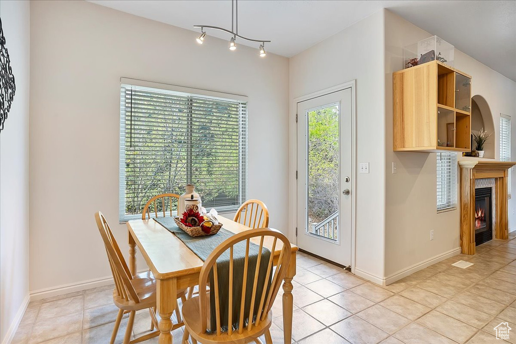Dining area with baseboards, light tile patterned floors, and a lit fireplace