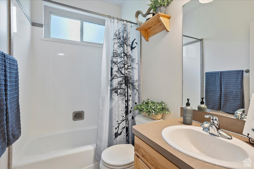 Full bathroom featuring toilet, vanity, and shower / bath combination with curtain