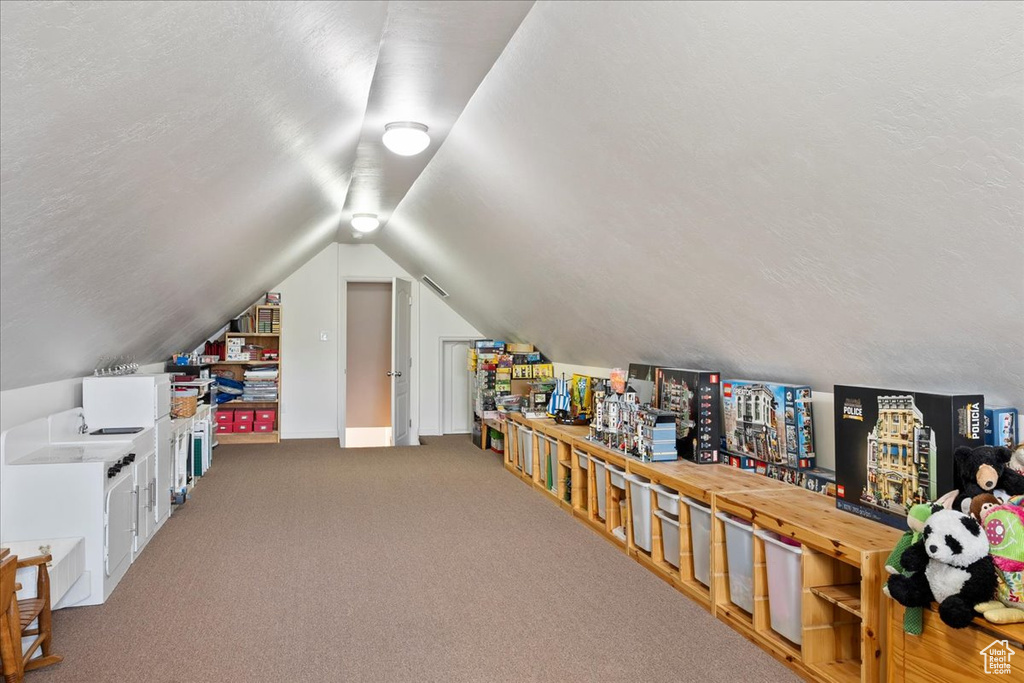 Recreation room with a textured ceiling, vaulted ceiling, and carpet floors