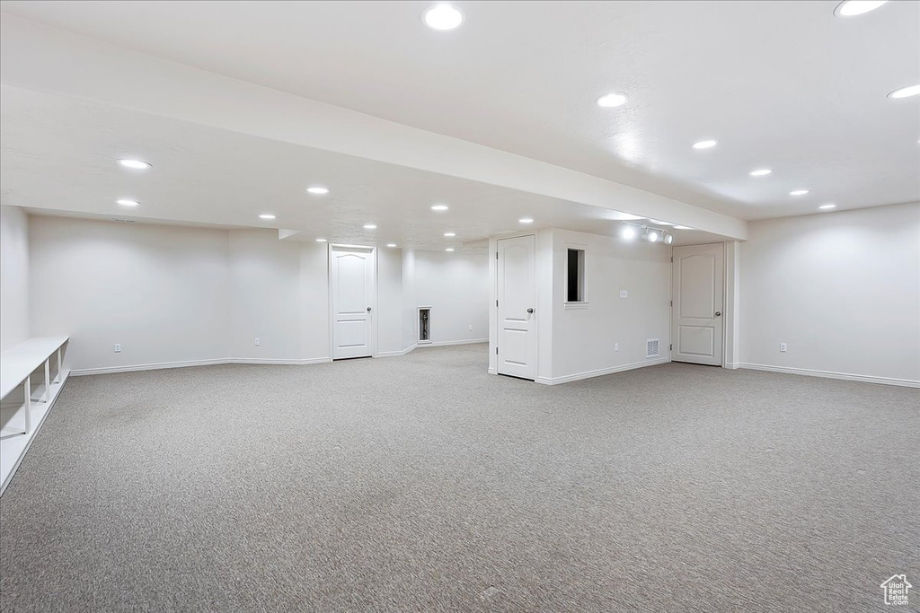 Finished below grade area featuring light colored carpet and recessed lighting