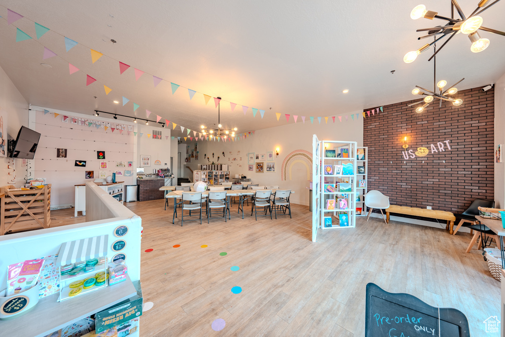 Recreation room with wood finished floors, brick wall, and a chandelier