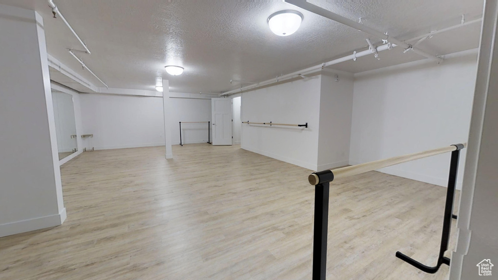 Finished basement featuring baseboards, a textured ceiling, and wood finished floors