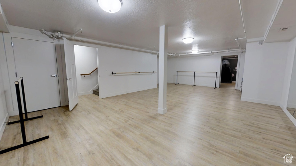 Finished basement featuring baseboards, visible vents, wood finished floors, and stairway