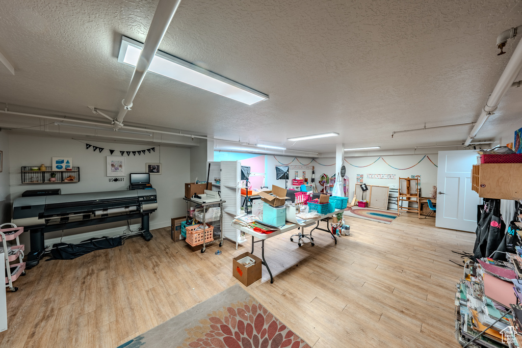 Finished basement featuring a textured ceiling and wood finished floors