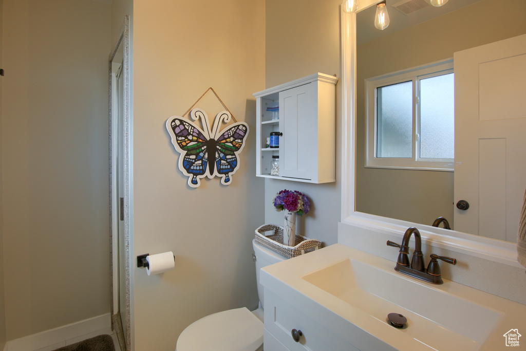 Bathroom featuring vanity, curtained shower, visible vents, and toilet