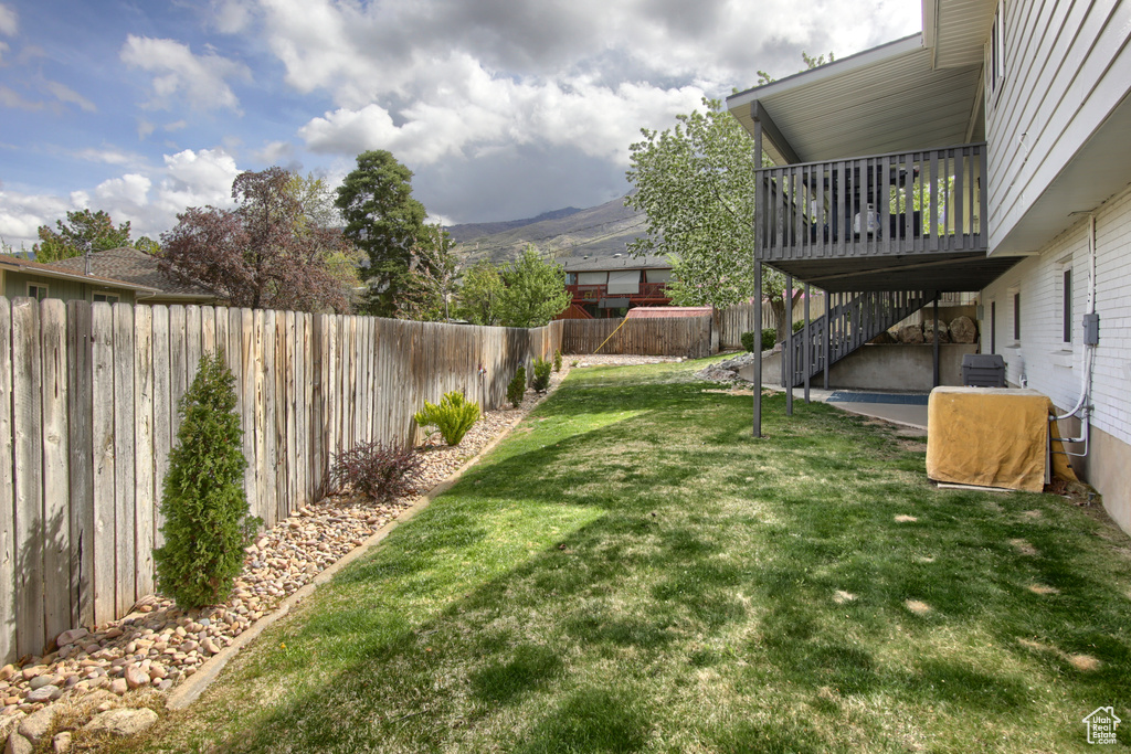 View of yard featuring stairs, a fenced backyard, and a deck with mountain view