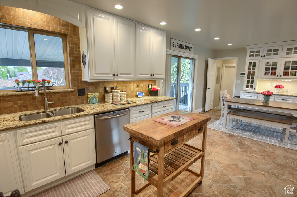 Kitchen featuring white cabinetry, decorative backsplash, a sink, and dishwasher