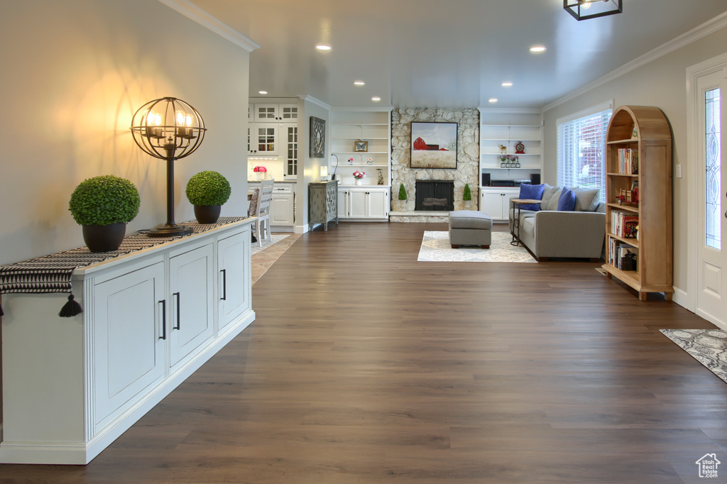 Living area with dark wood-style flooring, recessed lighting, ornamental molding, and a fireplace