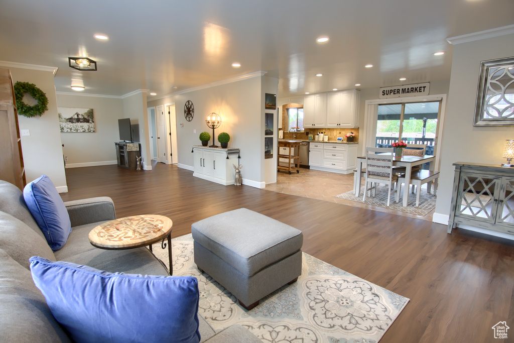 Living area with crown molding, recessed lighting, baseboards, and wood finished floors