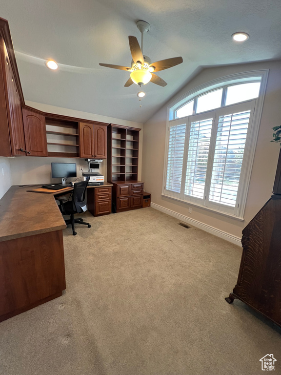 Office area featuring ceiling fan, light colored carpet, built in study area, baseboards, and vaulted ceiling