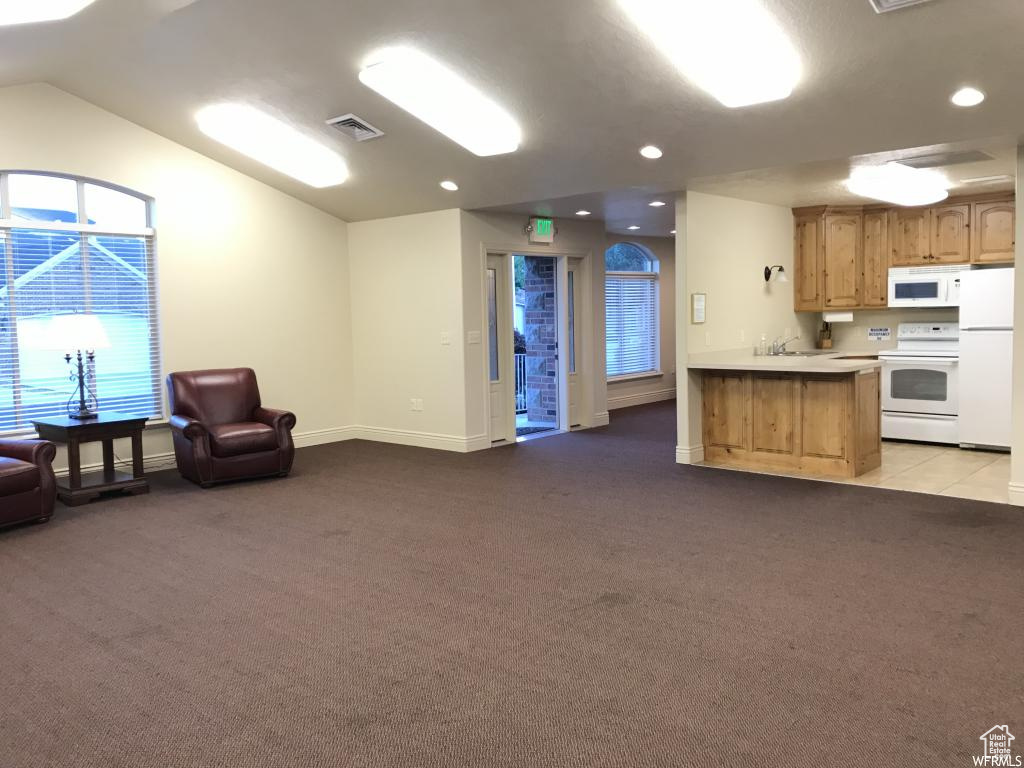 Kitchen with white appliances, open floor plan, visible vents, and light carpet
