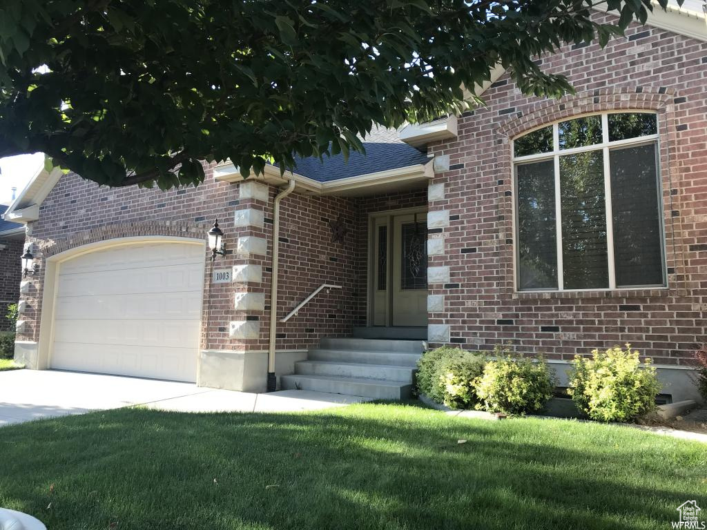 View of front of property with a garage, a front yard, driveway, and brick siding