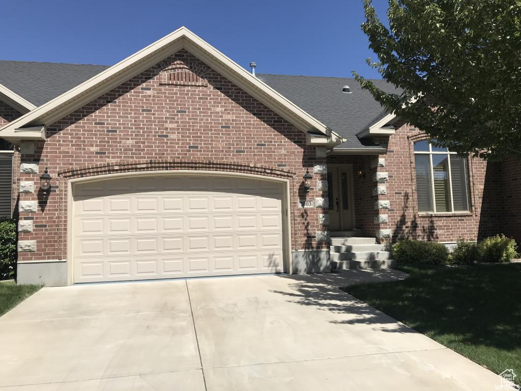 View of front of property featuring brick siding, a garage, roof with shingles, and concrete driveway