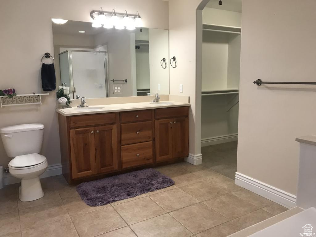 Bathroom featuring double vanity, toilet, a shower stall, and a sink