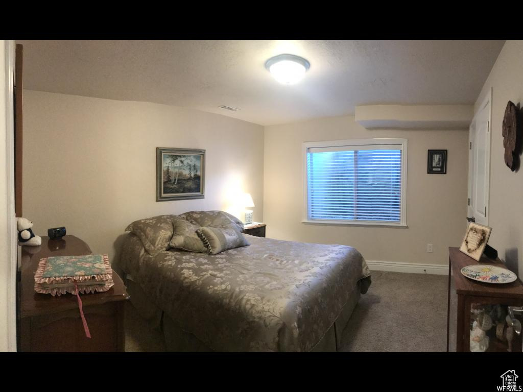 Carpeted bedroom featuring baseboards and visible vents