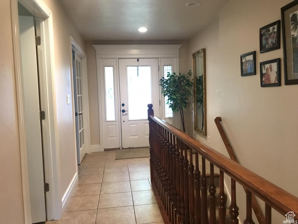Doorway with baseboards and light tile patterned floors