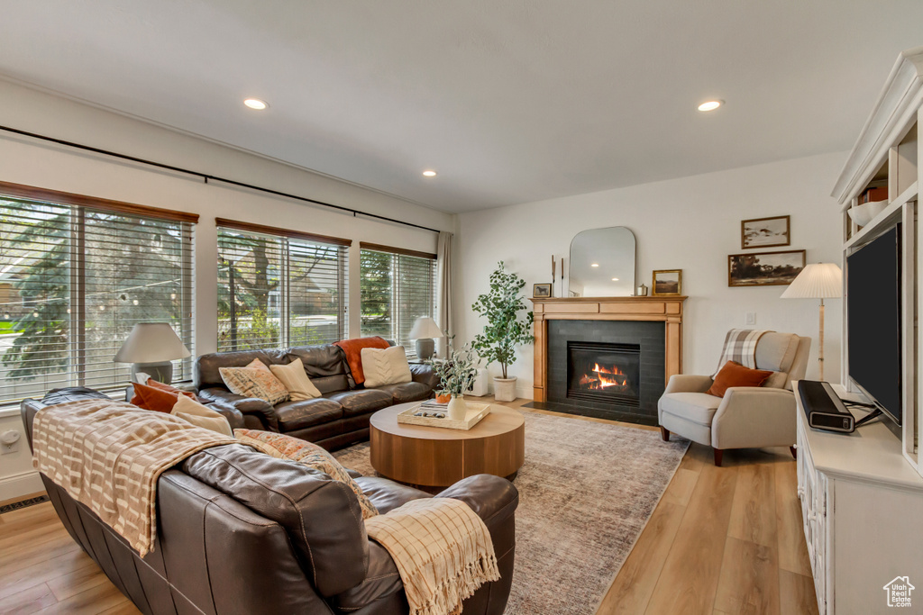 Living area featuring a fireplace with flush hearth, light wood-type flooring, and recessed lighting