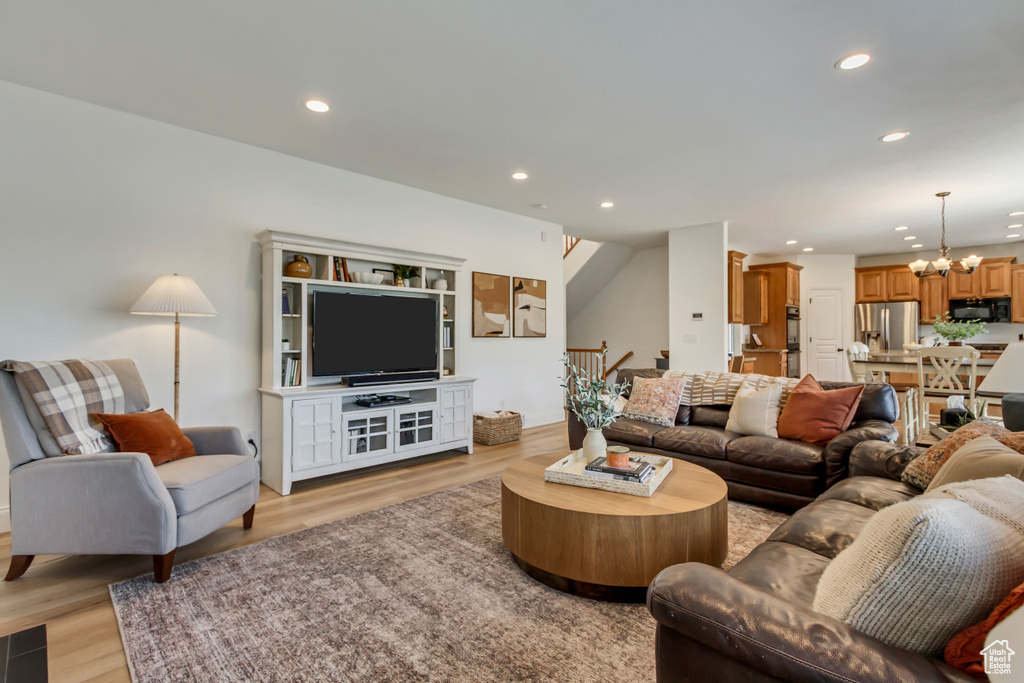 Living area featuring recessed lighting, an inviting chandelier, stairway, and light wood-style floors