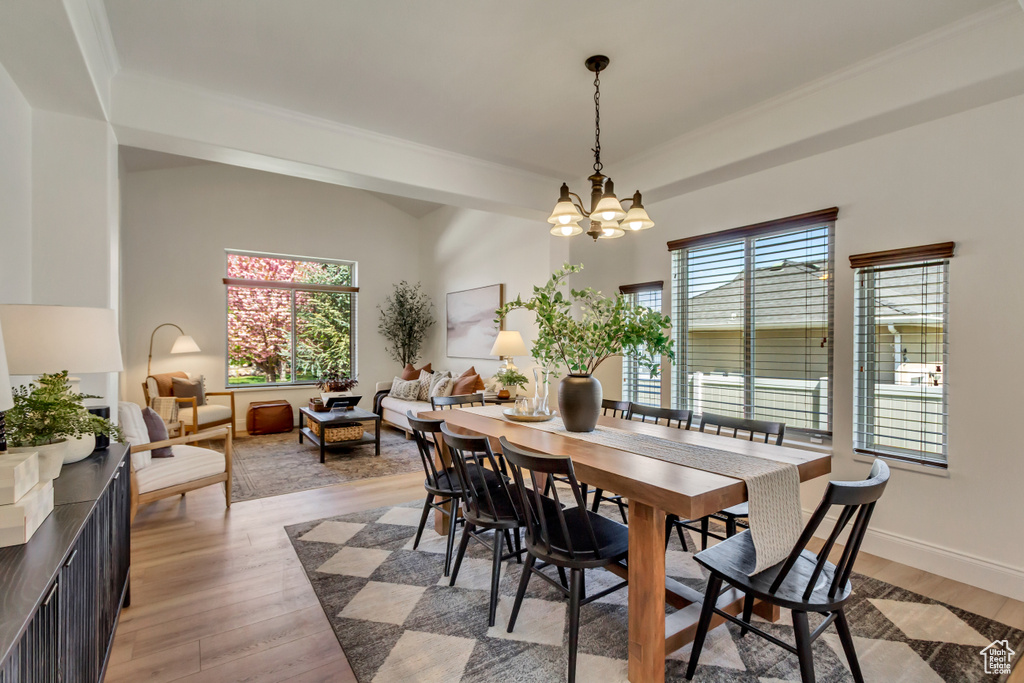 Dining area with ornamental molding, light wood finished floors, an inviting chandelier, and baseboards