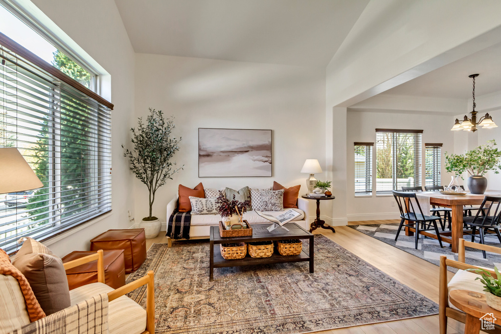 Living area with baseboards, wood finished floors, a notable chandelier, and vaulted ceiling