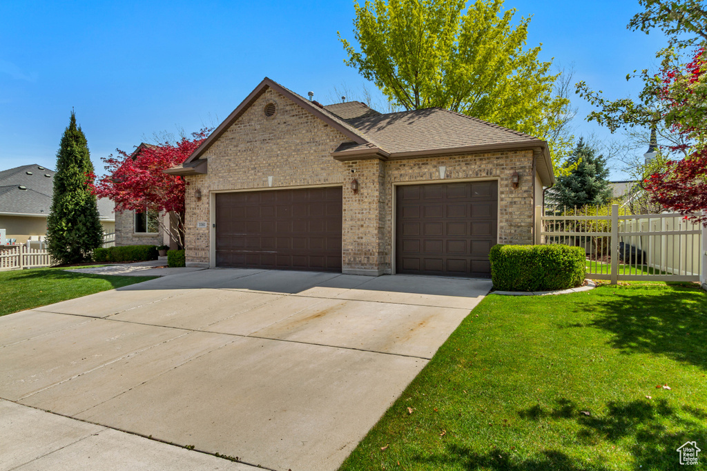 View of front of house featuring a garage, brick siding, a front lawn, and concrete driveway