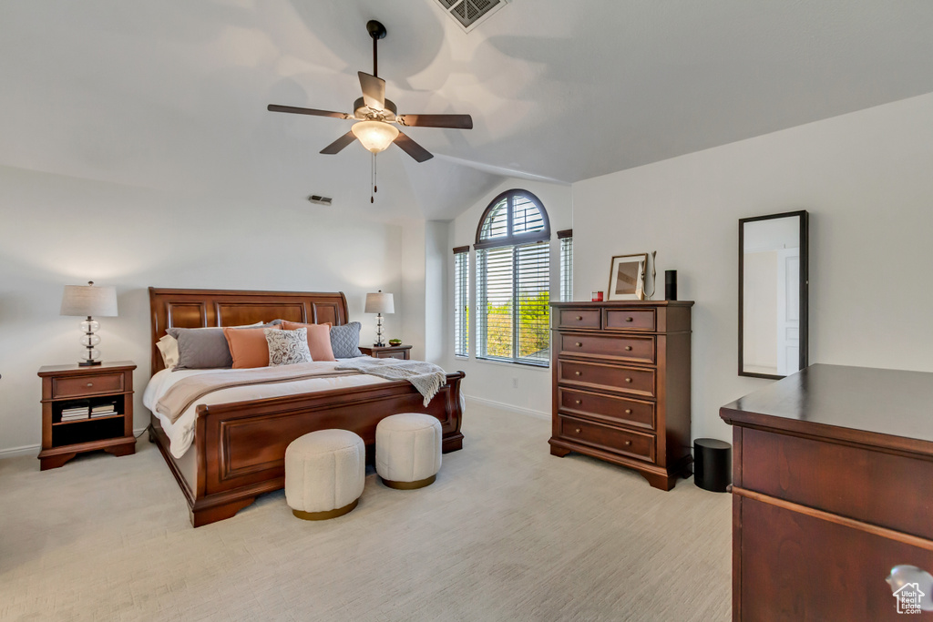 Bedroom with visible vents, vaulted ceiling, light carpet, and baseboards