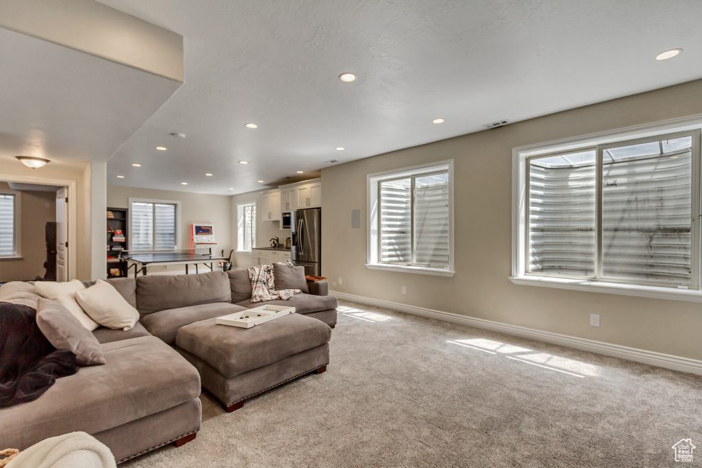 Living area featuring baseboards, recessed lighting, and light carpet