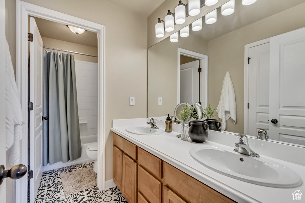 Bathroom featuring double vanity, toilet, tile patterned floors, and a sink
