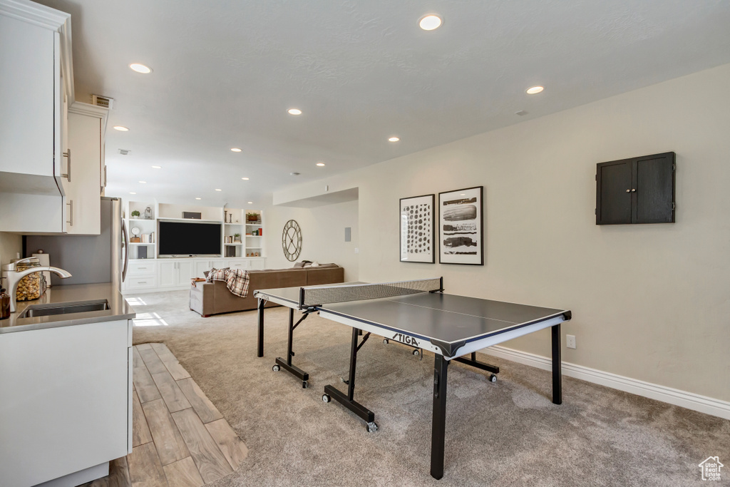 Recreation room with baseboards, recessed lighting, light colored carpet, and a sink