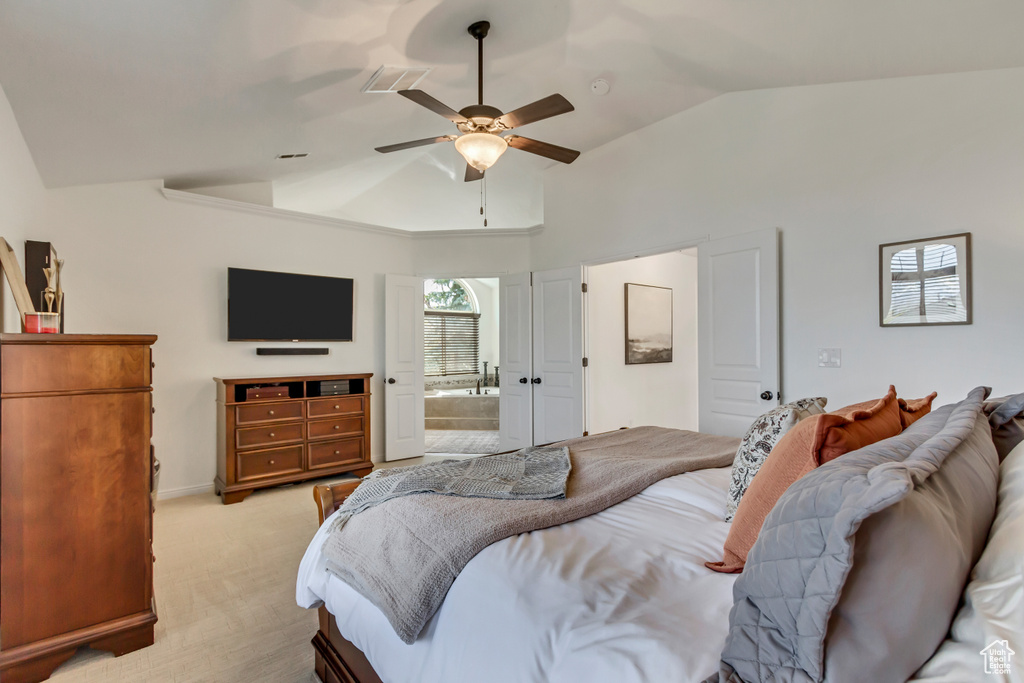 Bedroom with ceiling fan, high vaulted ceiling, visible vents, light carpet, and ensuite bathroom