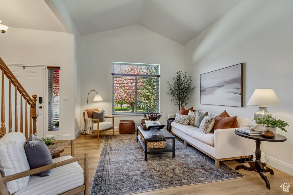Living room featuring baseboards, wood finished floors, stairs, and vaulted ceiling