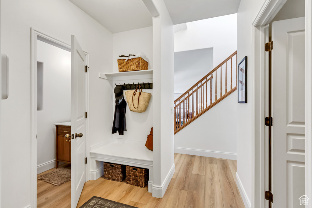 Mudroom featuring light wood finished floors, arched walkways, and baseboards