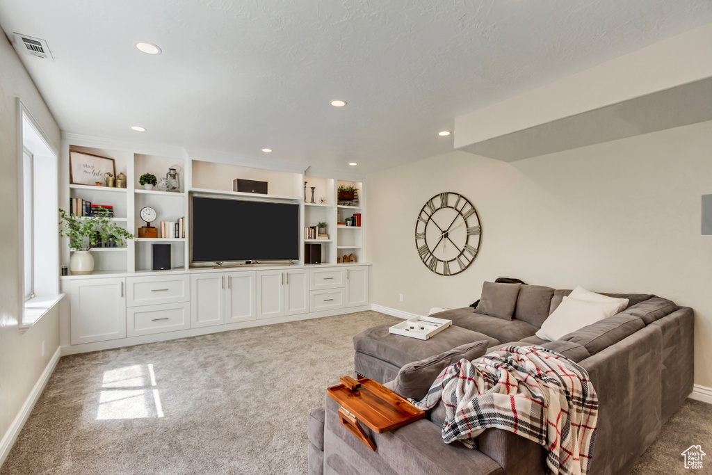 Living area with baseboards, light colored carpet, and a healthy amount of sunlight