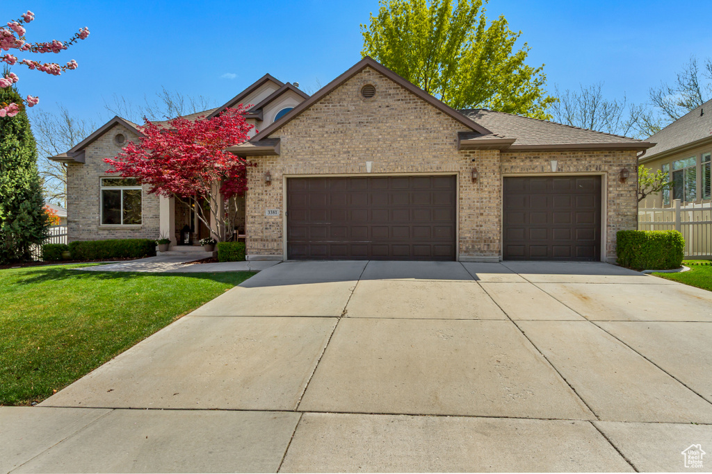 View of front of property featuring concrete driveway, a front yard, fence, brick siding, and a garage