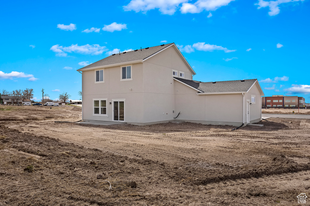Rear view of house with a shingled roof and stucco siding