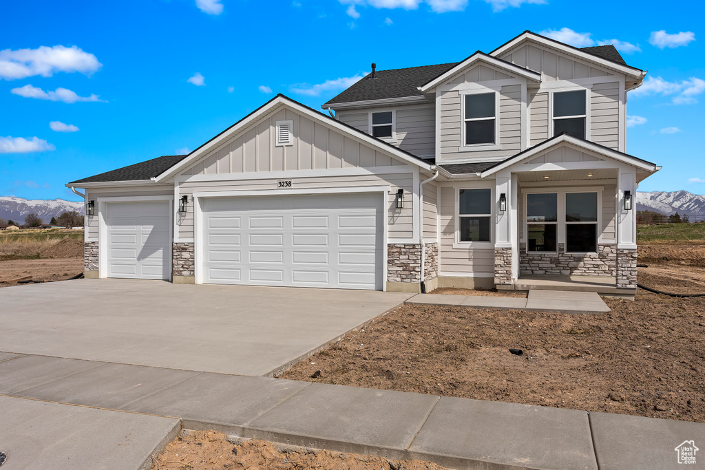 Craftsman-style home featuring an attached garage, board and batten siding, a mountain view, and stone siding