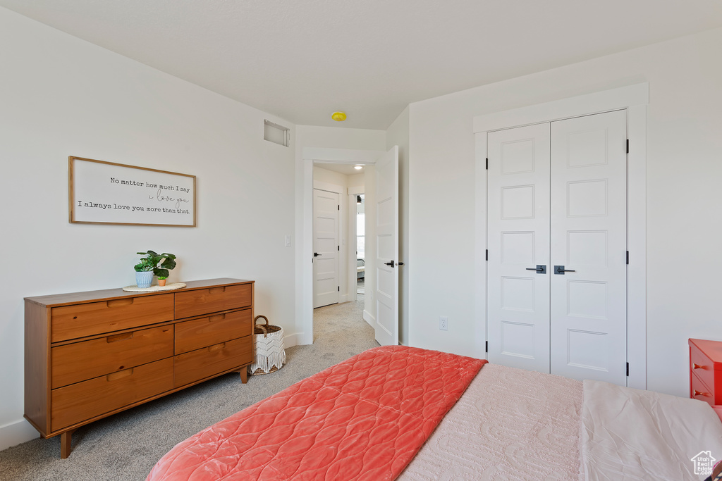 Bedroom with light colored carpet, baseboards, visible vents, and a closet