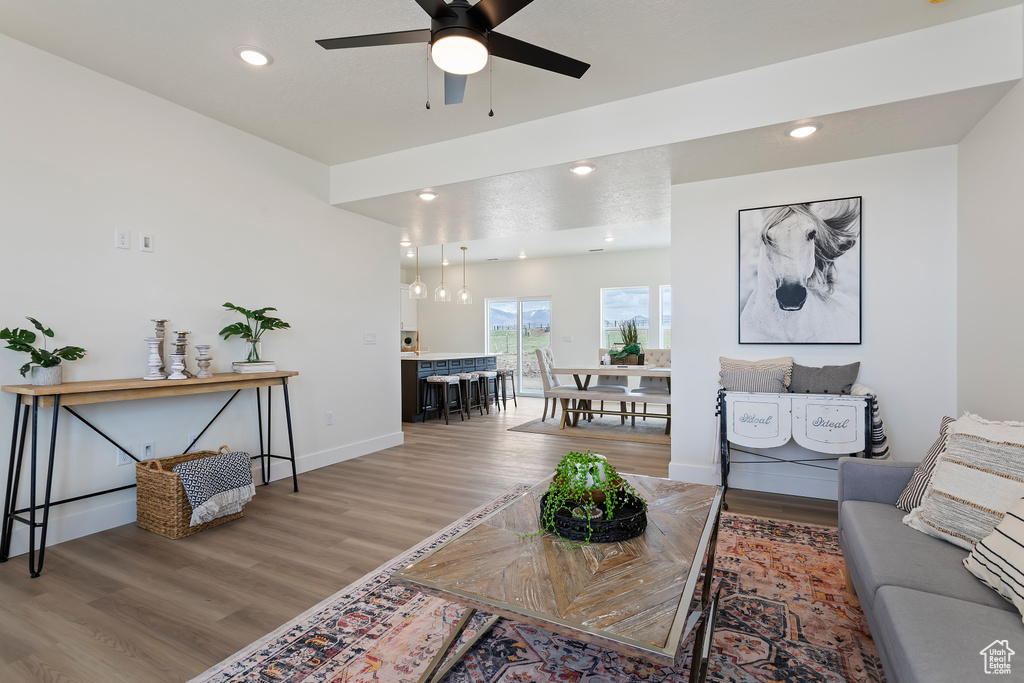 Living area featuring a ceiling fan, baseboards, recessed lighting, and light wood finished floors