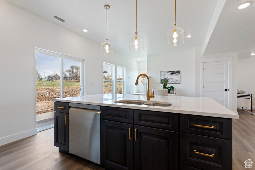 Kitchen featuring a sink, dark cabinets, stainless steel dishwasher, and light countertops