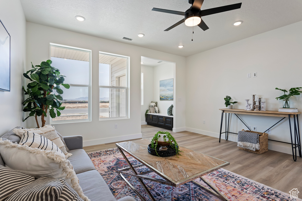 Living room with light wood-style floors, a ceiling fan, baseboards, and recessed lighting