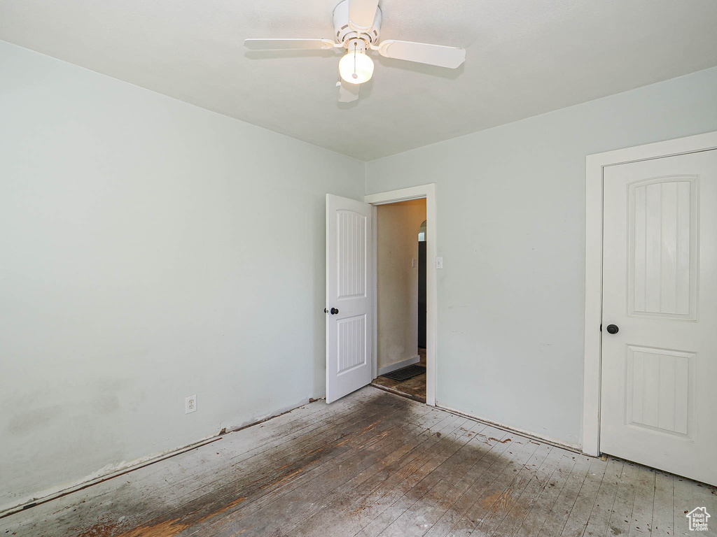 Empty room with a ceiling fan and hardwood / wood-style floors