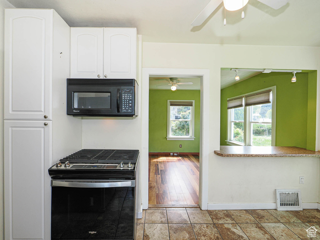 Kitchen with white cabinets, a ceiling fan, visible vents, and black appliances