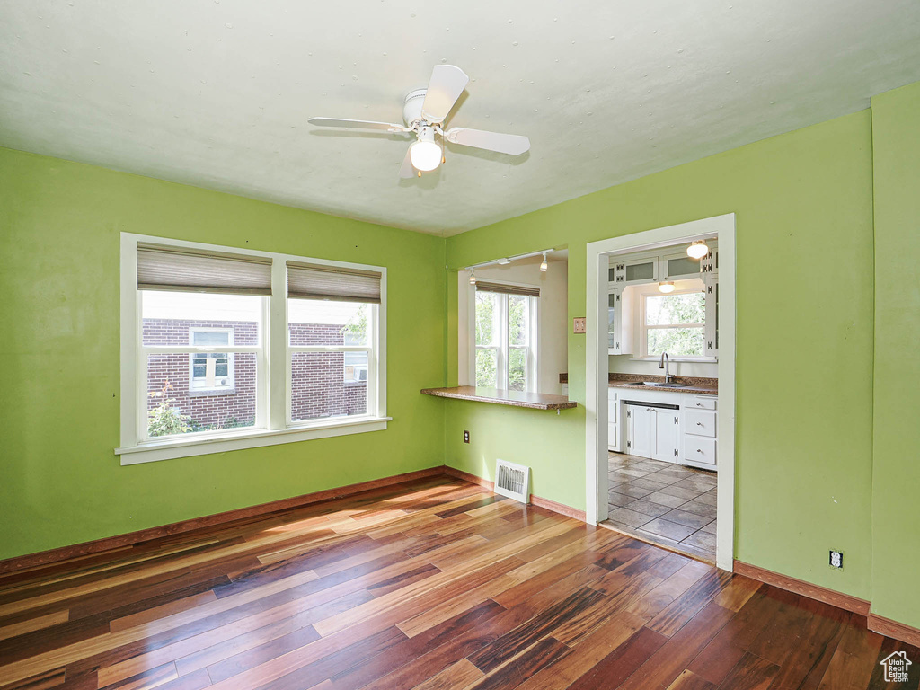 Empty room with visible vents, a ceiling fan, wood finished floors, baseboards, and a sink