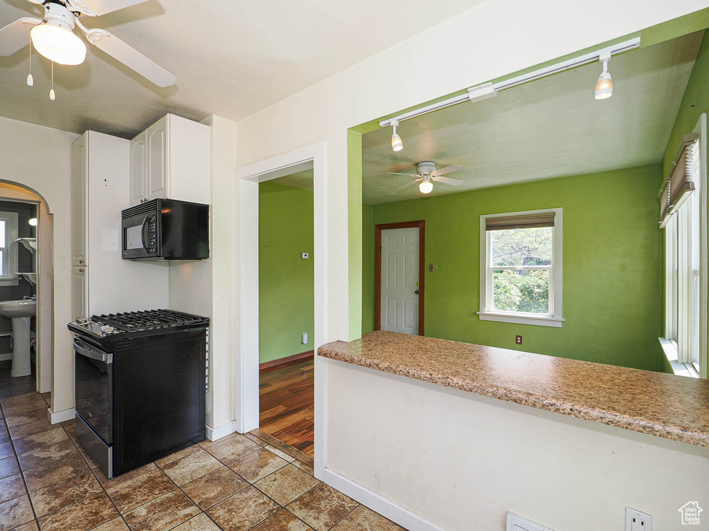 Kitchen with ceiling fan, arched walkways, rail lighting, white cabinetry, and black appliances