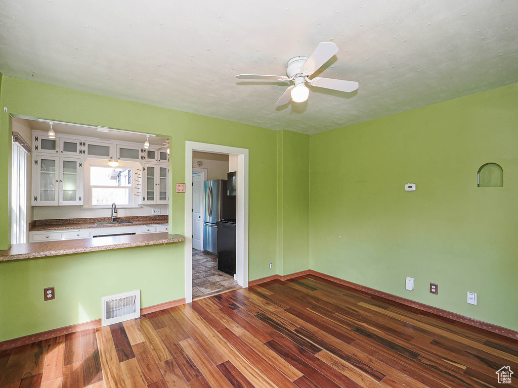 Kitchen featuring ceiling fan, a sink, white cabinetry, wood finished floors, and visible vents