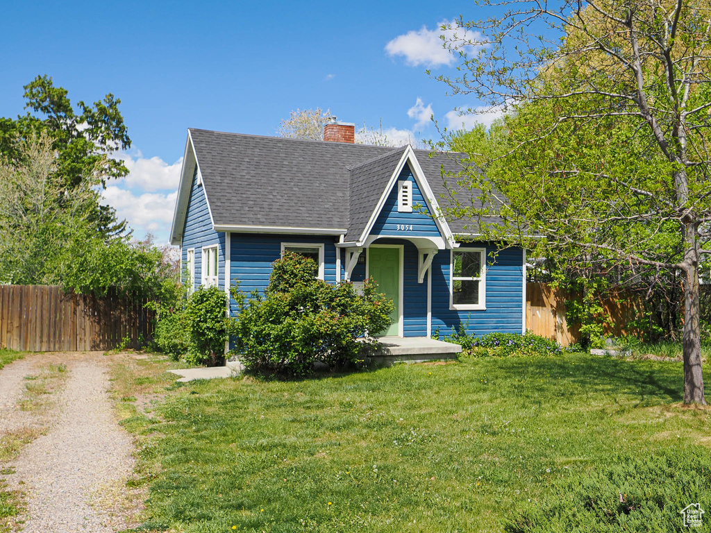 Bungalow-style home featuring fence, a chimney, driveway, and a front lawn